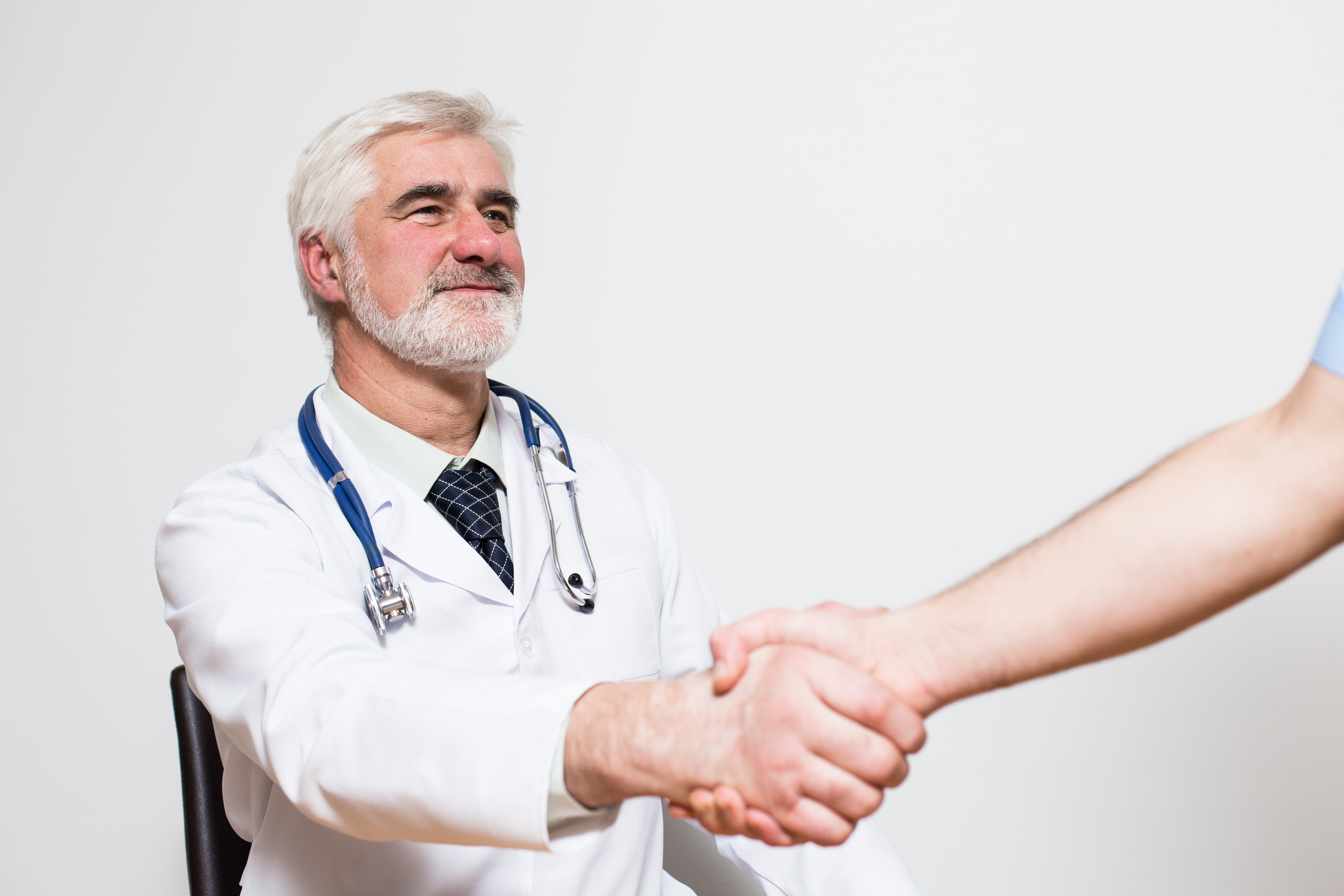 middle aged doctor with gray hair and beard making handshake