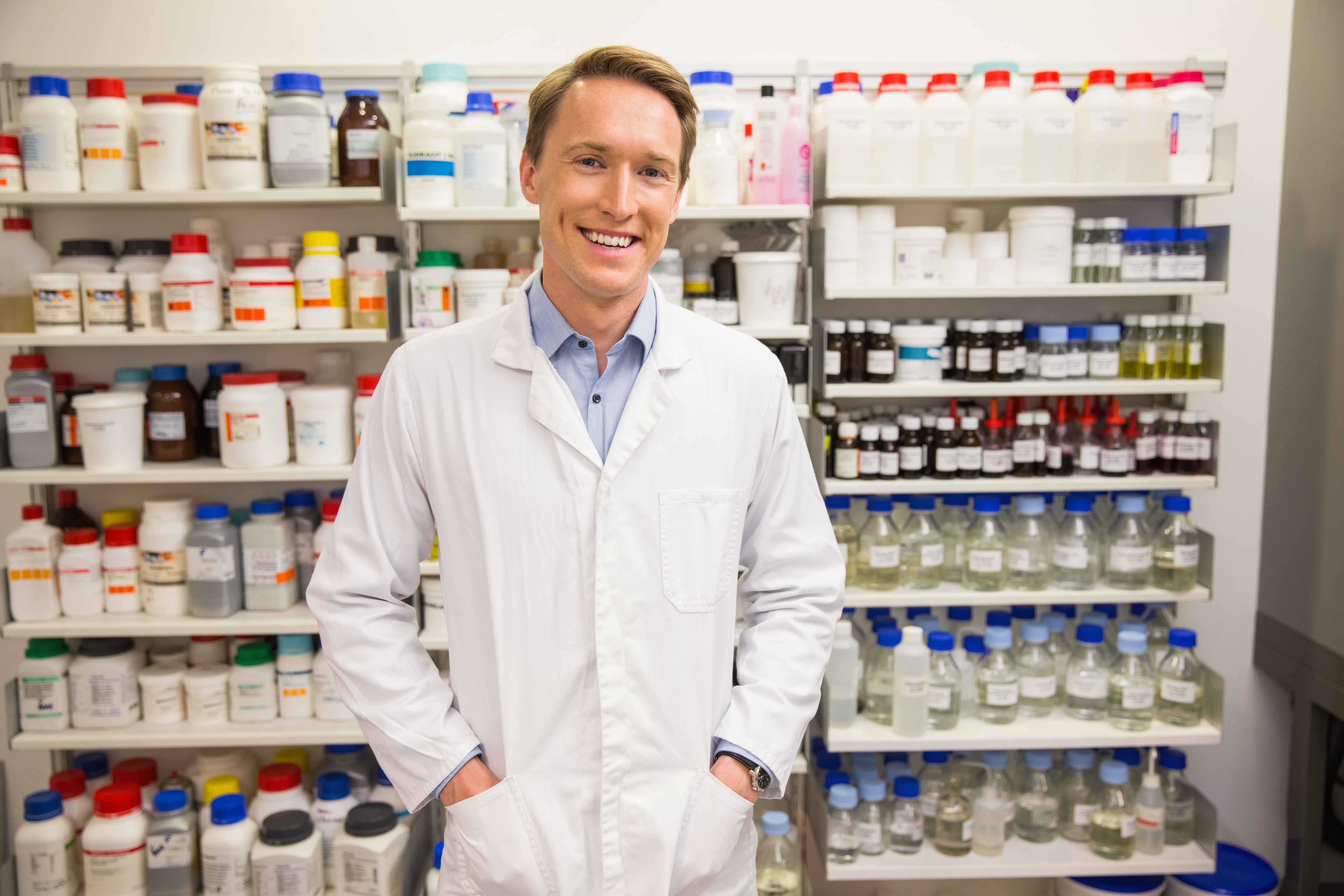 Handsome pharmacist smiling at camera at the hospital pharmacy